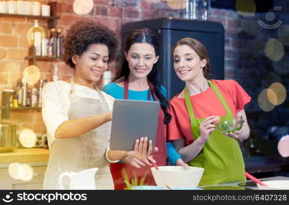 cooking class, friendship, food, technology and people concept - happy women with tablet pc computer in kitchen. happy women with tablet pc cooking in kitchen