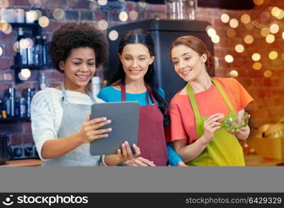 cooking class, friendship, food, technology and people concept - happy women with tablet pc computer in kitchen. happy women with tablet pc cooking in kitchen