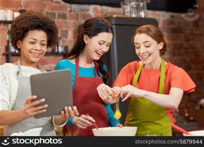 cooking class, friendship, food, technology and people concept - happy women with tablet pc in kitchen