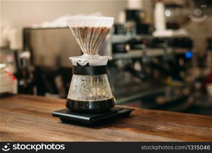 Cooking coffee in a glass pot on bar counter. Blury coffee house on background.. Cooking coffee in a glass pot on bar counter.