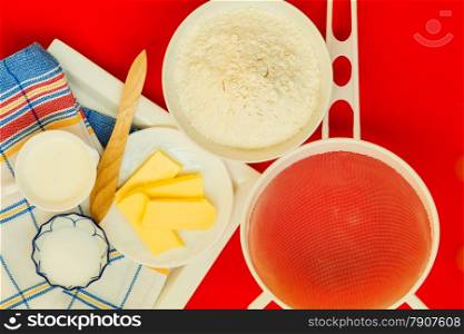 Cooking concept. Preparation for baking, bake ingredients and kitchen tools to make a cake on red nonstick silicone mat, top view