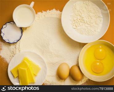 Cooking concept. Preparation for baking, bake ingredients and kitchen tools to make a cake on orange nonstick silicone mat, top view
