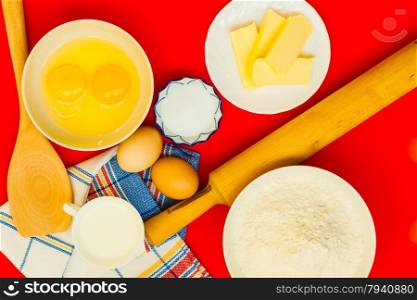 Cooking concept. Preparation for baking, bake ingredients and kitchen tools to make a cake on red nonstick silicone mat, top view