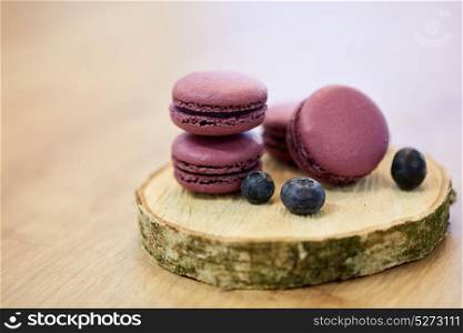 cooking, confectionery and baking concept - blueberry macarons on wooden stand. blueberry macarons on wooden stand