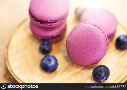 cooking, confectionery and baking concept - blueberry macarons on wooden stand. blueberry macarons on wooden stand
