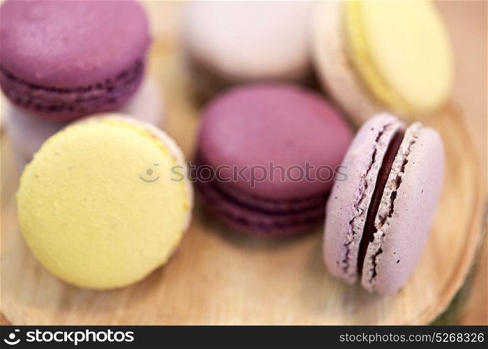cooking, confectionery and baking concept - close up of different macarons on wooden stand. close up of different macarons on wooden stand