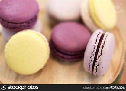 cooking, confectionery and baking concept - close up of different macarons on wooden stand. close up of different macarons on wooden stand