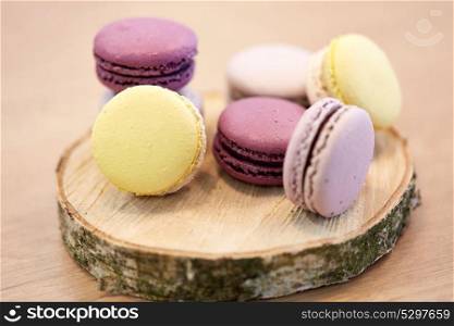cooking, confectionery and baking concept - different macarons on wooden stand. different macarons on wooden stand