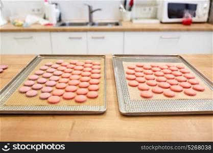 cooking, confectionery and baking concept - macarons on oven trays at bakery or pastry shop kitchen. macarons on oven trays at confectionery