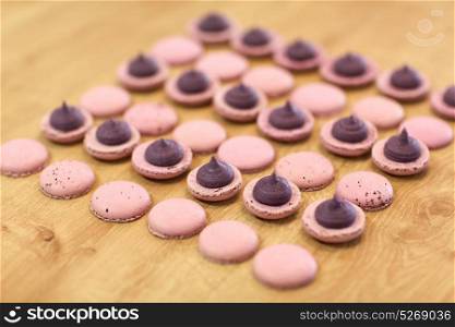 cooking, confectionery and baking concept - macarons with buttercream filling on table at bakery. macarons on table at confectionery or bakery