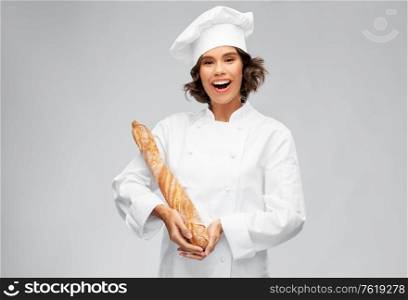 cooking, culinary and bakery concept - happy smiling female chef or baker in toque holding french bread or baguette over grey background. happy female chef with french bread or baguette