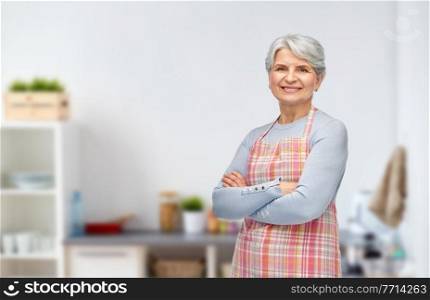 cooking, culinary and old people concept - portrait of smiling senior woman in apron over kitchen background. portrait of smiling senior woman in kitchen apron