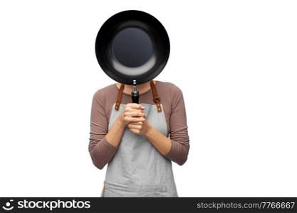 cooking, culinary and people concept - female chef in apron hiding face behind frying pan over white background. female chef hiding face behind frying pan