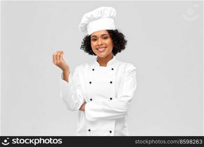 cooking, culinary and people concept - happy female chef in toque and white jacket showing gourmet sign over grey background. happy female chef showing gourmet sign