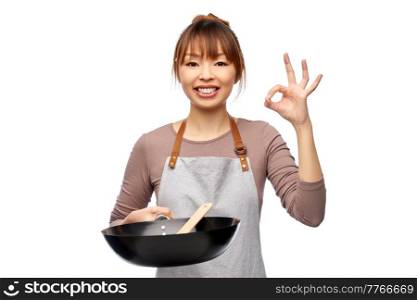 cooking, culinary and people concept - happy smiling female chef in apron with frying pan and spatula showing ok gesture over white background. happy woman with frying pan showing ok gesture