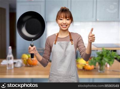 cooking, culinary and people concept - happy smiling female chef in apron with frying pan showing thumbs up over home kitchen background. happy female chef with frying pan in kitchen