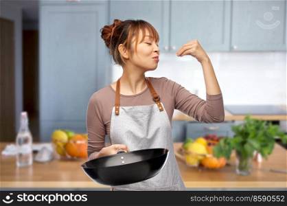 cooking, culinary and people concept - happy smiling female chef in apron with frying pan making gourmet gesture over home kitchen background. happy female chef with frying pan in kitchen