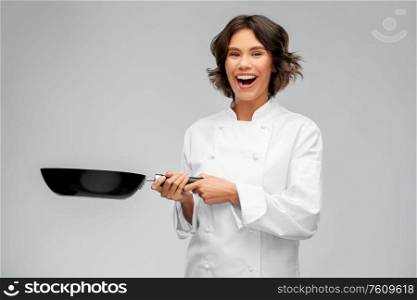cooking, culinary and people concept - happy smiling female chef in toque with frying pan over grey background. smiling female chef in toque with frying pan