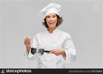 cooking, culinary and people concept - happy smiling female chef in toque with saucepan over grey background. happy smiling female chef with saucepan