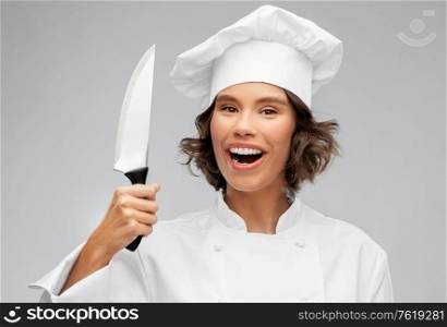 cooking, culinary and people concept - happy smiling female chef in toque with kitchen knife over grey background. smiling female chef in toque with kitchen knife