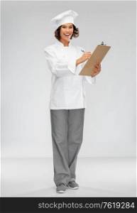 cooking, culinary and people concept - happy smiling female chef in toque with clipboard and pen over grey background. smiling female chef in toque with clipboard