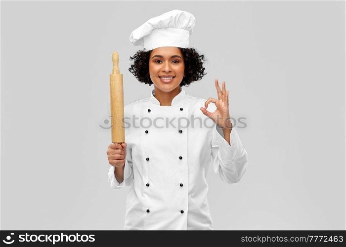 cooking, culinary and people concept - happy smiling female chef in toque or baker with rolling pin over grey background. smiling female chef or baker with rolling pin