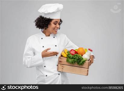 cooking, culinary and people concept - happy smiling female chef in toque holding food in wooden box over grey background. happy smiling female chef with food in wooden box