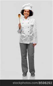 cooking, culinary and people concept - happy smiling female chef in toque with wooden spoon over grey background. smiling female chef with wooden spoon
