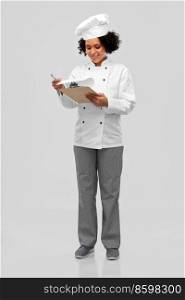 cooking, culinary and people concept - happy smiling female chef in toque and jacket with papers on clipboard over grey background. smiling female chef with papers on clipboard