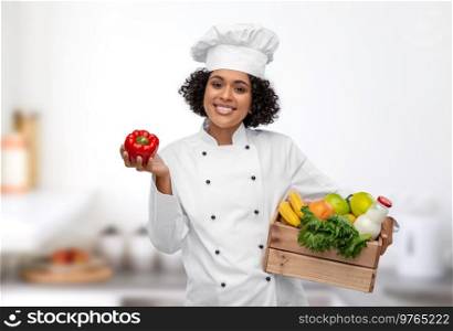 cooking, culinary and people concept - happy smiling female chef in toque holding food in wooden box and red pepper over restaurant kitchen background. female chef with food in wooden box in kitchen