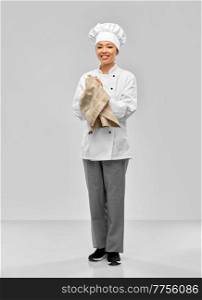 cooking, culinary and people concept - happy smiling female chef in white jacket with kitchen towel over grey background. smiling female chef in jacket with kitchen towel