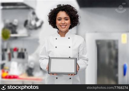 cooking, culinary and people concept - happy smiling female chef in white jacket showing tablet pc computer over restaurant kitchen background. smiling female chef showing tablet pc on kitchen