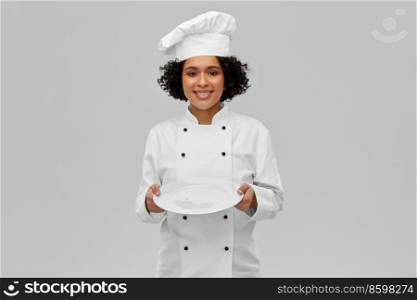 cooking, culinary and people concept - happy smiling female chef in white toque and jacket holding empty plate over grey background. happy smiling female chef holding empty plate