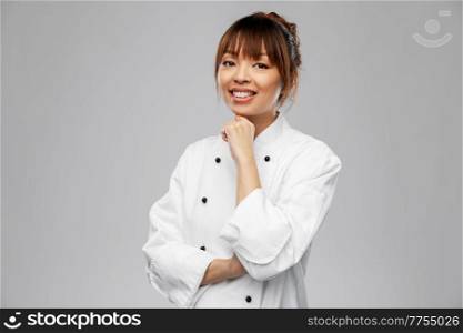 cooking, culinary and people concept - happy smiling female chef in white jacket over grey background. smiling female chef in white jacket