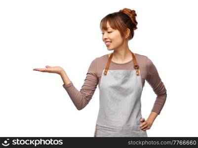 cooking, culinary and people concept - happy smiling female chef or waitress in apron holding something imaginary on her hand over white background. happy female chef or waitress holding something