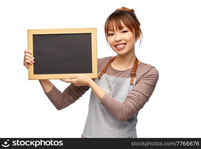 cooking, culinary and people concept - happy smiling female chef or waitress in apron with chalkboard over white background. happy woman in apron with chalkboard