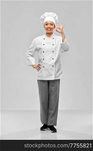 cooking, culinary and people concept - happy smiling female chef showing ok hand sign over grey background. happy smiling female chef showing ok hand sign