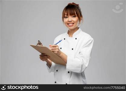 cooking, culinary and people concept - happy smiling female chef with clipboard and pen over grey background. smiling female chef with clipboard and pen