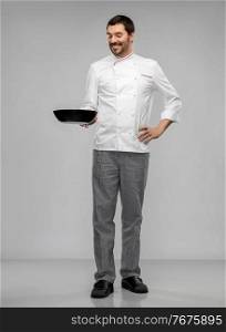 cooking, culinary and people concept - happy smiling male chef in jacket with frying pan over grey background. happy smiling male chef in jacket with frying pan