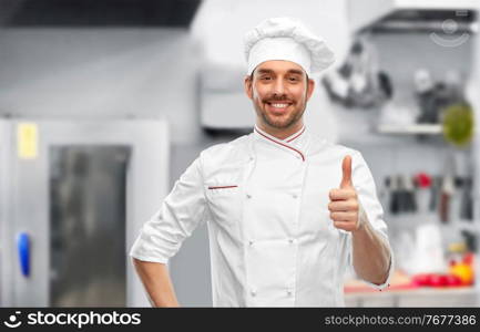 cooking, culinary and people concept - happy smiling male chef in toque showing thumbs up over restaurant kitchen background. smiling male chef in toque showing thumbs up