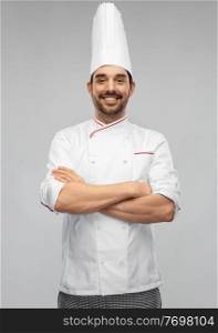 cooking, culinary and people concept - happy smiling male chef in toque and jacket with crossed arms over grey background. happy smiling male chef in toque with crossed arms