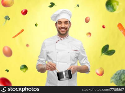 cooking, culinary and people concept - happy smiling male chef in toque with pot or saucepan over vegetables on illuminating yellow background. happy smiling male chef with saucepan cooking food