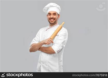 cooking, culinary and people concept - happy smiling male chef or baker in toque with rolling pin over grey background. happy smiling male chef or baker with rolling pin