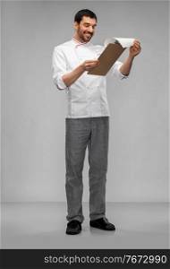 cooking, culinary and people concept - happy smiling male chef with clipboard and pencil over grey background. happy smiling male chef with clipboard