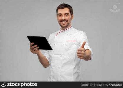 cooking, culinary and people concept - happy smiling male chef with tablet pc computer showing thumbs up over grey background. happy male chef with tablet pc showing thumbs up