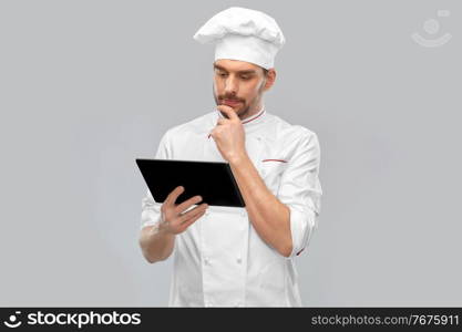 cooking, culinary and people concept - male chef in toque with tablet pc computer over grey background. male chef with tablet pc computer