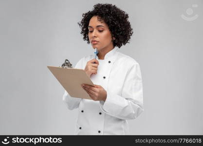 cooking, culinary and people concept - thinking female chef in white jacket with clipboard and pen over grey background. thinking female chef with clipboard and pen
