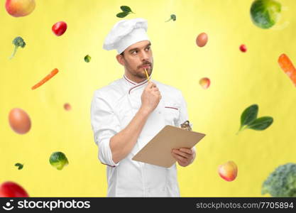 cooking, culinary and people concept - thinking male chef with clipboard and pencil over vegetables on illuminating yellow background. thinking male chef with clipboard