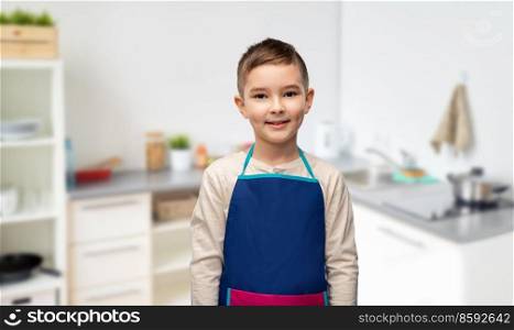 cooking, culinary and profession concept - happy smiling little boy in apron over home kitchen background. smiling little boy in apron in kitchen