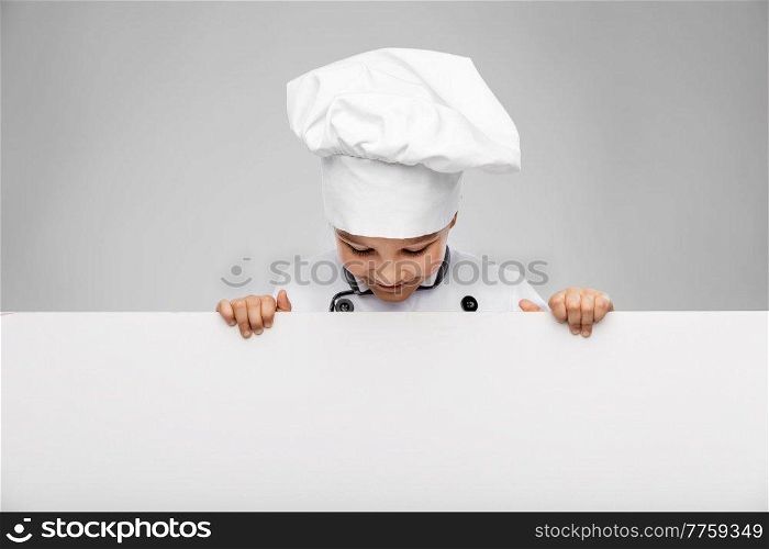 cooking, culinary and profession concept - happy smiling little girl in chef&rsquo;s toque and jacket looking at white board over grey background. happy little girl in chef&rsquo;s toque with white board